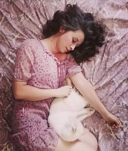 Mujer relajada junto a su gato, disfrutando del calor que calma los cólicos menstruales y conecta con el autocuidado