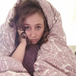 Imagen de mujer entre sábanas, mostrando cómo aliviar y cuidar el cuerpo durante los síntomas del síndrome premenstrual