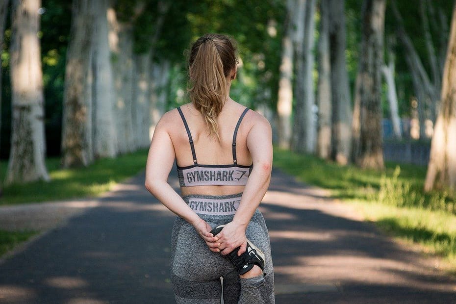 Mujer estirando antes de correr, mostrando los beneficios del ejercicio físico para la salud hormonal femenina